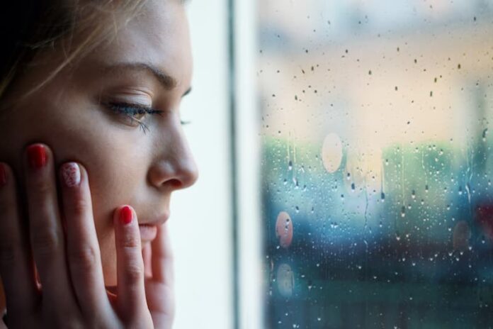 Eine Frau sitzt vor dem Fenster, was ist soziale Isolation?