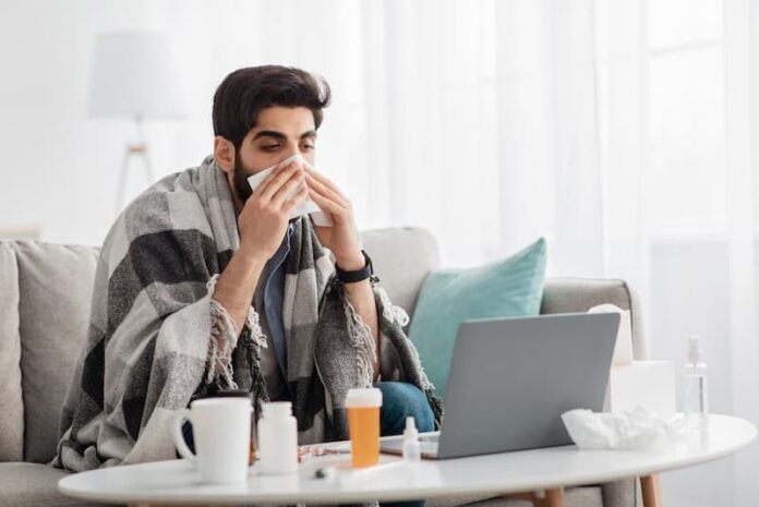 Ein Mann sitzt mit einer Erkältung Zuhause, wie kann man sich krankschreiben lassen?