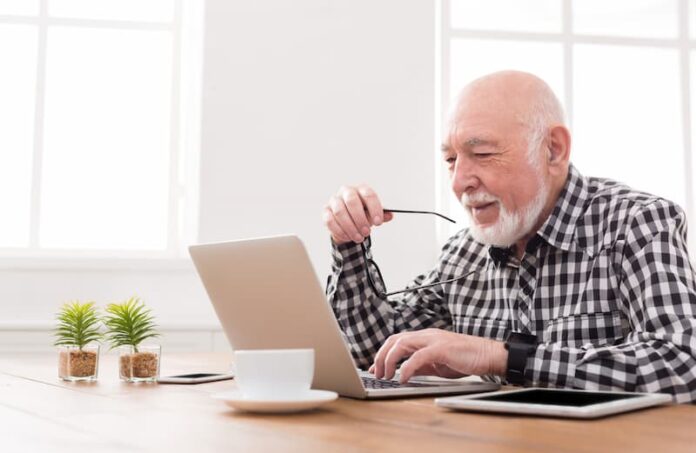 Ein alter Mann sitzt am Computer, was ist Digital Divide?