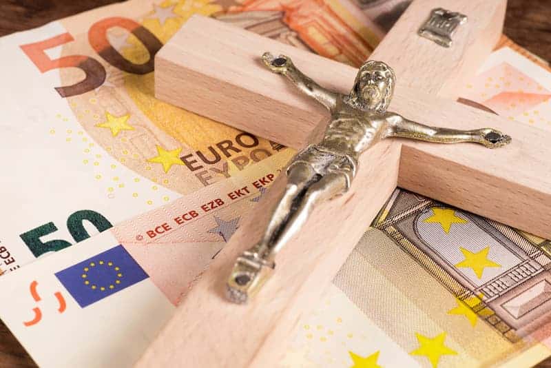 Ein christliches Kreuz auf Geldscheinen, was ist die Kirchensteuer?