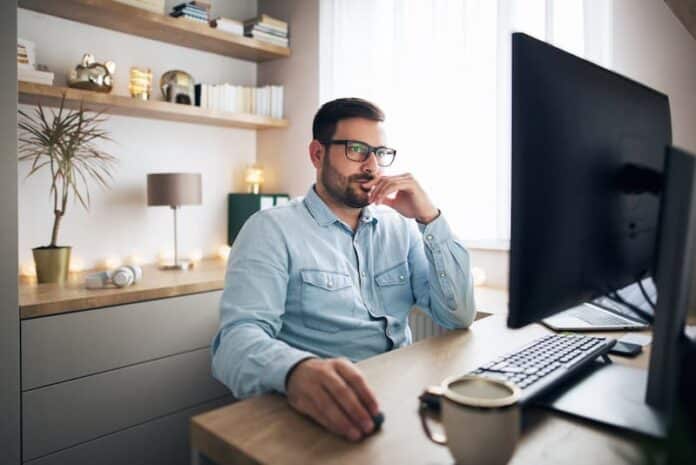 Ein Mann sitzt Zuhause am PC, was ist hybrides Arbeiten?