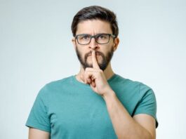 Ein Mann hält einen Finger vor den Mund, was ist die Schweigepflicht?