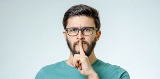 Ein Mann hält einen Finger vor den Mund, was ist die Schweigepflicht?