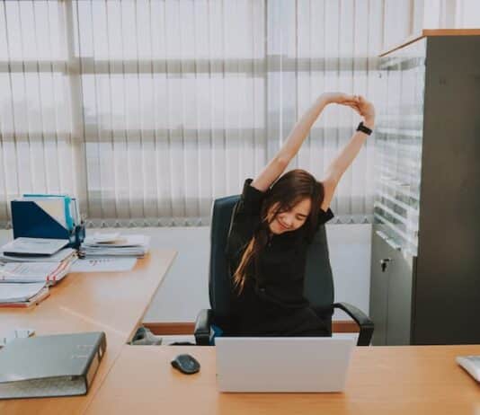 Eine Frau streckt sich im Büro, was ist Sport im Büro?