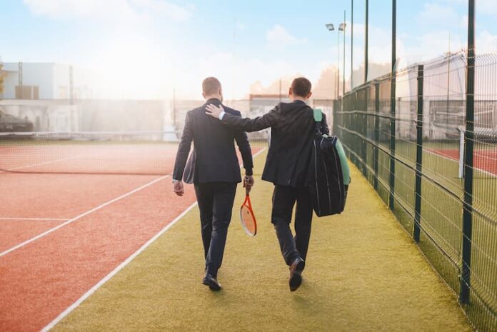 Zwei Männer im Anzug mit Tennisschlägern, was ist Sport nach der Arbeit?
