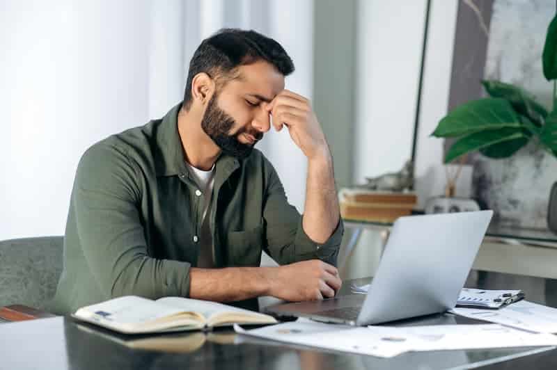 Ein Mann sitzt krank vor dem Laptop, gibt es eine Krankmeldung per E-Mail?