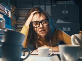 Eine Frau sitzt zwischen Aktenbergen, was tun bei Stress im Job?
