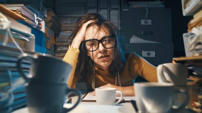 Eine Frau sitzt zwischen Aktenbergen, was tun bei Stress im Job?