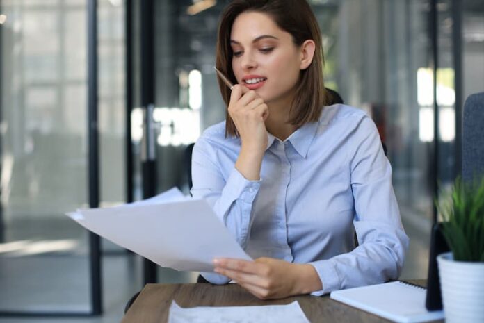 Eine Frau blickt auf Dokumente, was ist die freiwillige Arbeitslosenversicherung?