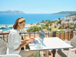 Eine Frau sitzt mit Laptop auf einer Terrasse, was ist Workation?