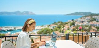 Eine Frau sitzt mit Laptop auf einer Terrasse, was ist Workation?