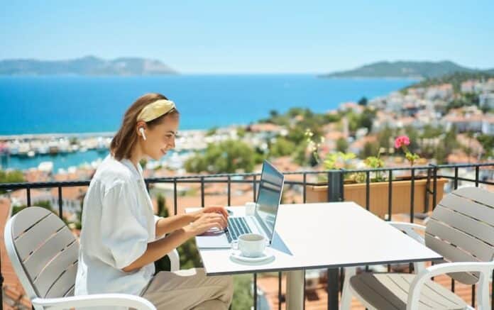 Eine Frau sitzt mit Laptop auf einer Terrasse, was ist Workation?