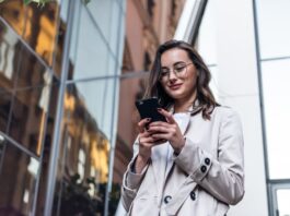 Eine Frau sieht auf das Smartphone, welche Bedeutung hat ständige Erreichbarkeit im Job?