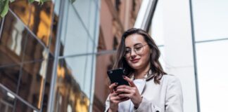 Eine Frau sieht auf das Smartphone, welche Bedeutung hat ständige Erreichbarkeit im Job?