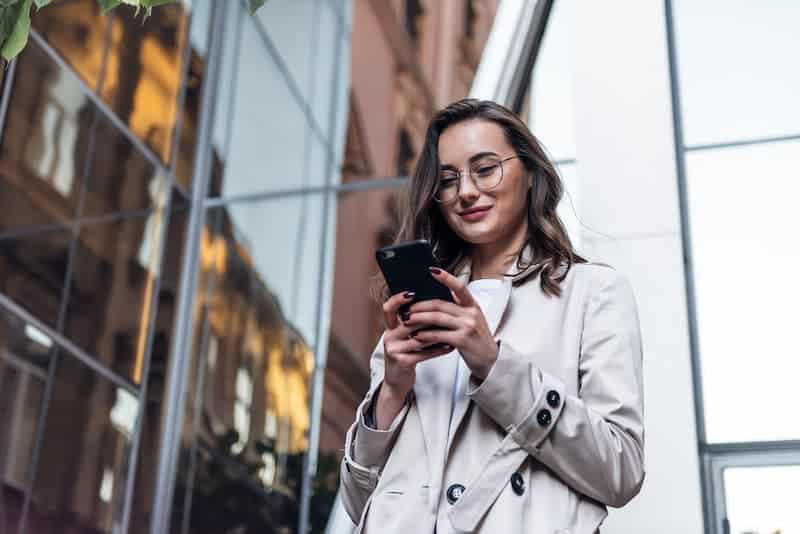 Eine Frau sieht auf das Smartphone, welche Bedeutung hat ständige Erreichbarkeit im Job?