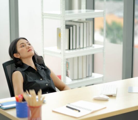 Eine Frau sitzt gelangweilt im Büro, was tun bei Unterforderung im Job?