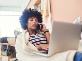 Eine Frau sitzt mit Decke am Laptop, was ist eine Teilzeit-Krankschreibung?