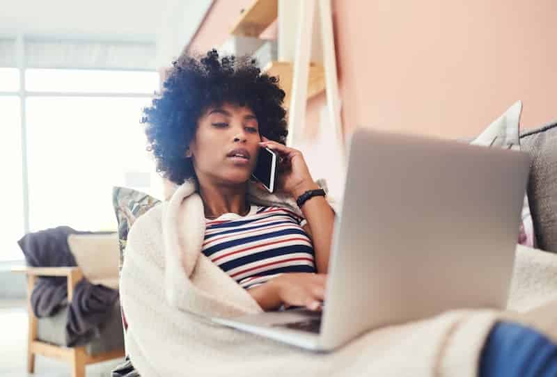 Eine Frau sitzt mit Decke am Laptop, was ist eine Teilzeit-Krankschreibung?