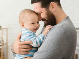 Ein Vater kuschelt im Vaterschaftsurlaub mit seinem Kind