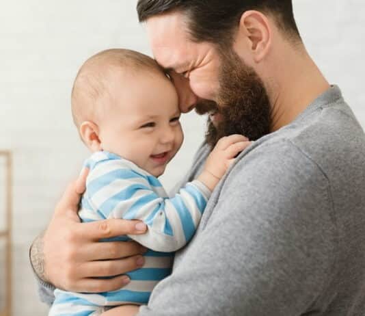 Ein Vater kuschelt im Vaterschaftsurlaub mit seinem Kind