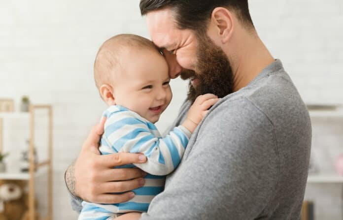 Ein Vater kuschelt im Vaterschaftsurlaub mit seinem Kind