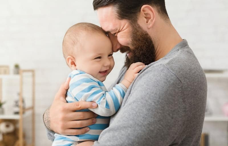 Ein Vater kuschelt im Vaterschaftsurlaub mit seinem Kind
