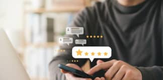 Ein Angestellter gibt seinem Arbeitgeber mit seinem Smartphone online eine gute öffentliche Bewertung. Das ist das Ergebnis von gutem Reputationsmanagement in Unternehmen.
