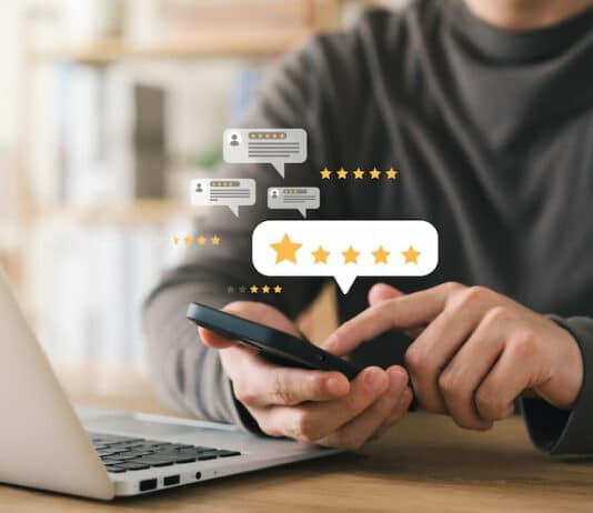 Ein Angestellter gibt seinem Arbeitgeber mit seinem Smartphone online eine gute öffentliche Bewertung. Das ist das Ergebnis von gutem Reputationsmanagement in Unternehmen.