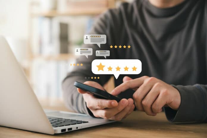 Ein Angestellter gibt seinem Arbeitgeber mit seinem Smartphone online eine gute öffentliche Bewertung. Das ist das Ergebnis von gutem Reputationsmanagement in Unternehmen.