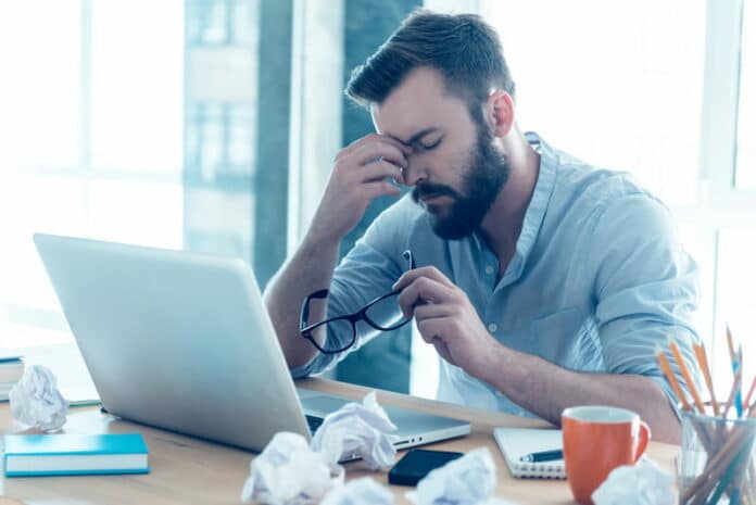 Ein Arbeitnehmer sitzt vor seinem Laptop und verspürt Frust im Job.