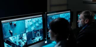 Nur herumsitzen? Was Arbeitsbereitschaft für deine Arbeitszeit bedeutet Zwei Sicherheitspersonen sitzen vor Monitoren, die Aufnahmen von Überwachungskameras zeigen, und sind in Arbeitsbereitschaft.