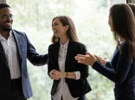 Vier Kollegen lachen gemeinsam und feiern ihren Erfolg. Gute Anreizsysteme motivieren sie.