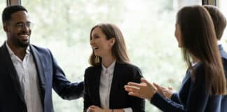 Anreizsysteme: Was zählt im Job wirklich neben dem Gehalt? Vier Kollegen lachen gemeinsam und feiern ihren Erfolg. Gute Anreizsysteme motivieren sie.