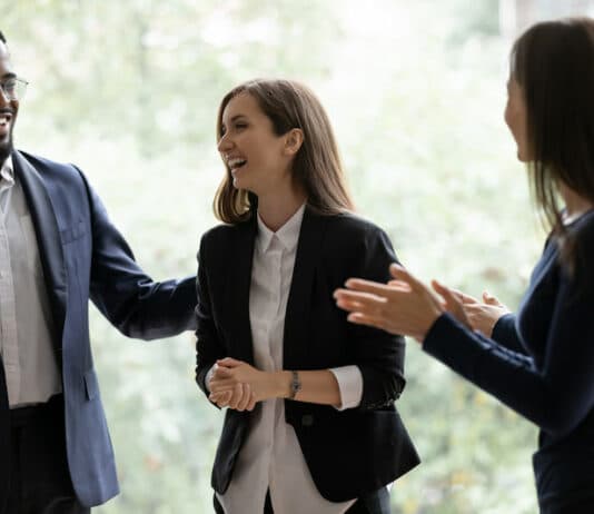 Vier Kollegen lachen gemeinsam und feiern ihren Erfolg. Gute Anreizsysteme motivieren sie.