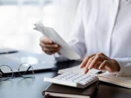 Eine Person tippt auf dem Taschenrechner. Sie berechnet Grundgehalt und Bonus.