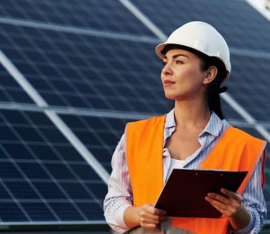 Ingenieurin steht mit Notizbrett vor Solarpanels. Ein Beispiel für Berufe mit Zukunft für Frauen.